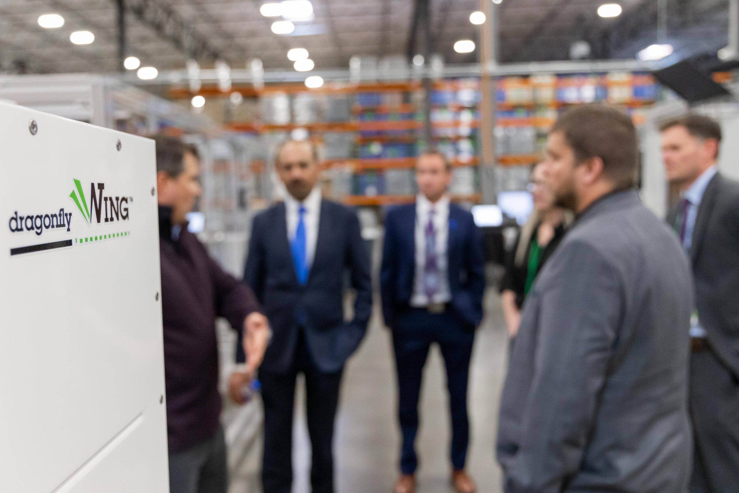 Dragonfly Energy's wing in focus. Men standing in suits out of focus.