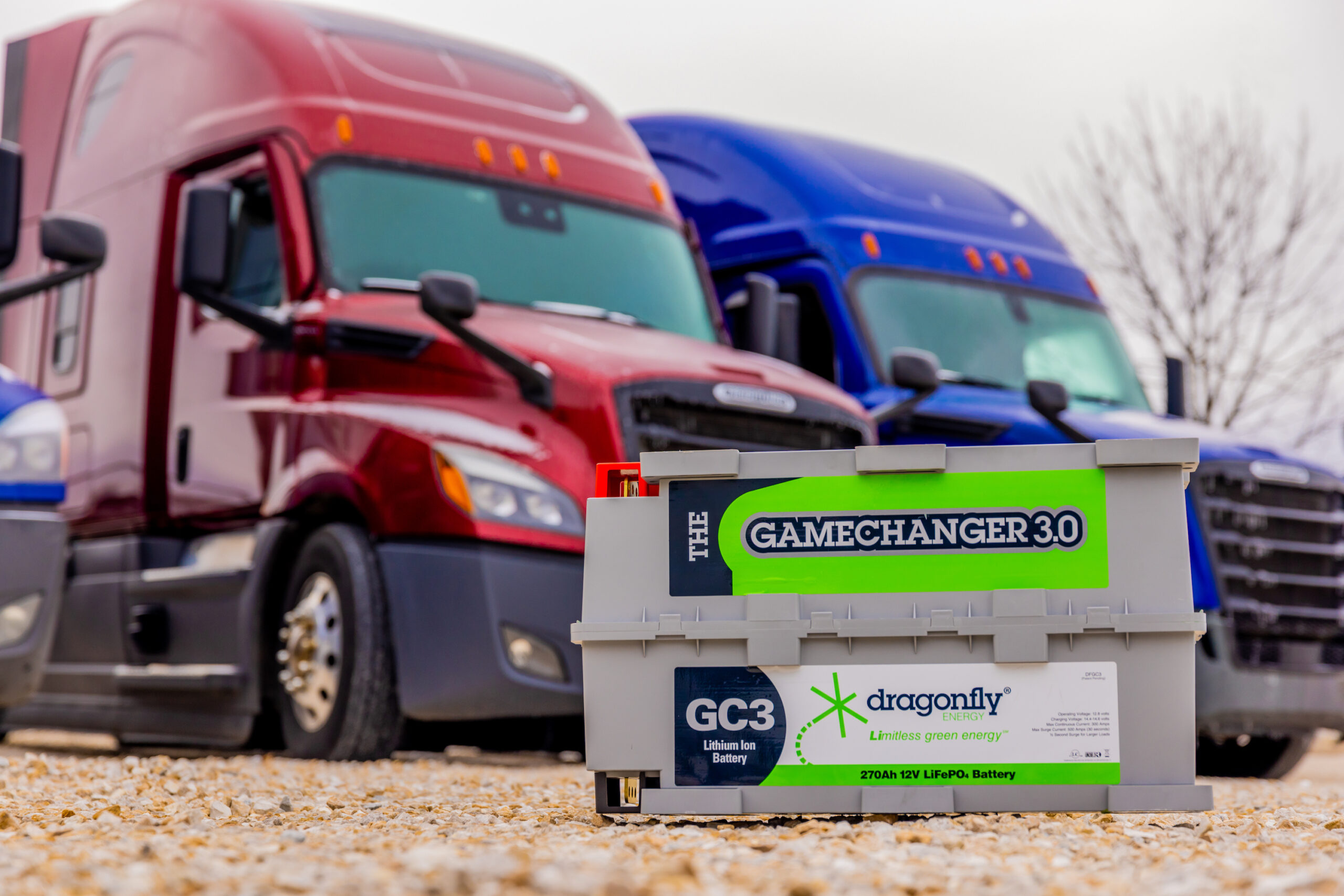 Dragonfly Energy's Gamechanger battery is a great option for long-haul trucking APUs. In this image it is placd in front of two long-haul trucks with sleepers.