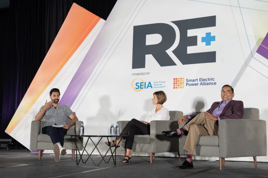 Panel of speakers sitting in chairs on stage at RE+
